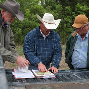 Roland reviewing plans with two land owners