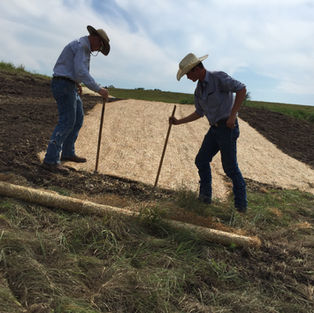 Two men working together to tack down the turf reinforcement mat