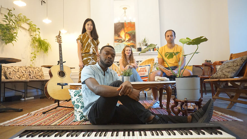 Members of O.N.E Band sitting and standing at Café Ambrose with instruments and plants in the background.