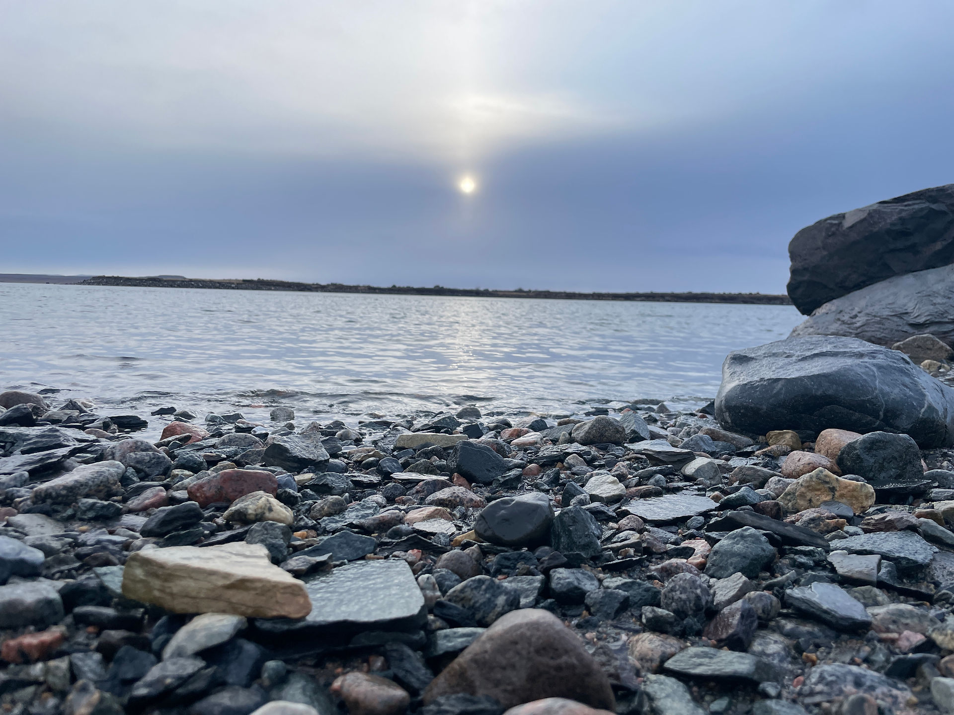 ocky shoreline under a pale winter sun reflecting on calm water