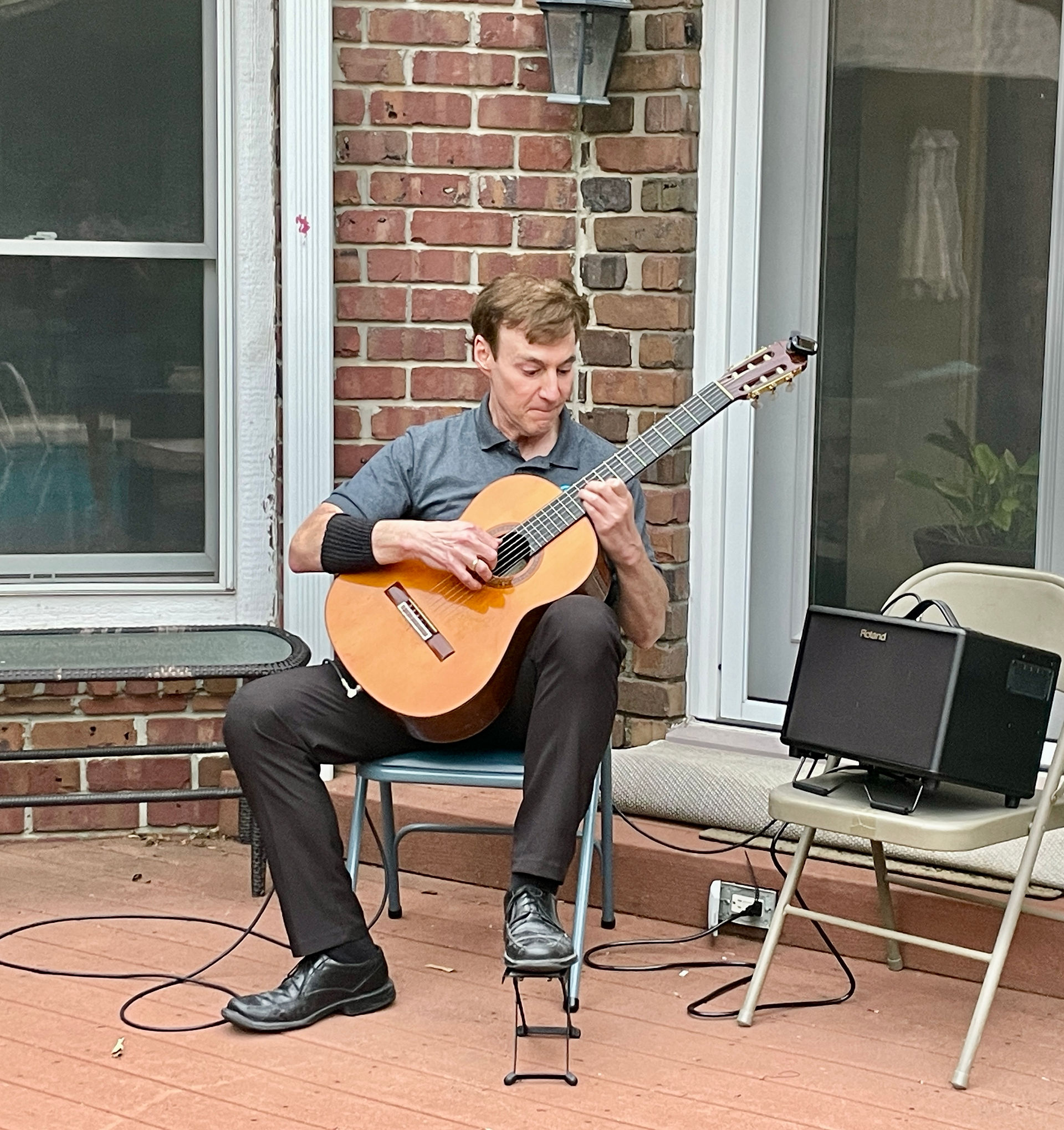 Dr. Nick Comninellis playing acoustic guitar outside during a relaxed evening gathering