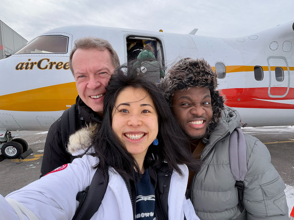 Three clinicians smiling in front of an Air Creebec turboprop aircraft on a snowy tarmac.
