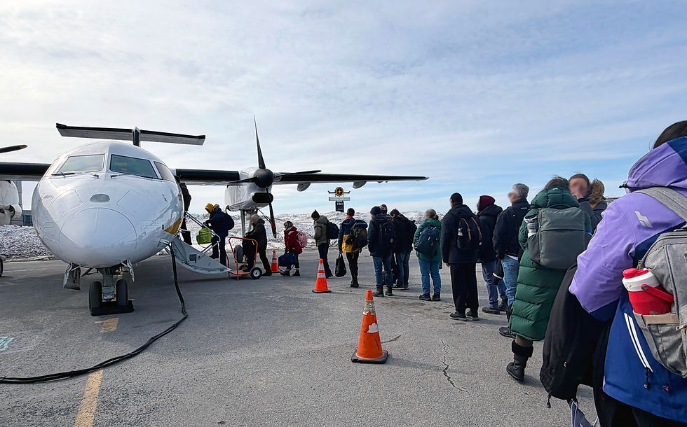 Passengers in winter coats lining up on the tarmac to board a small propeller plane in northern Quebec.