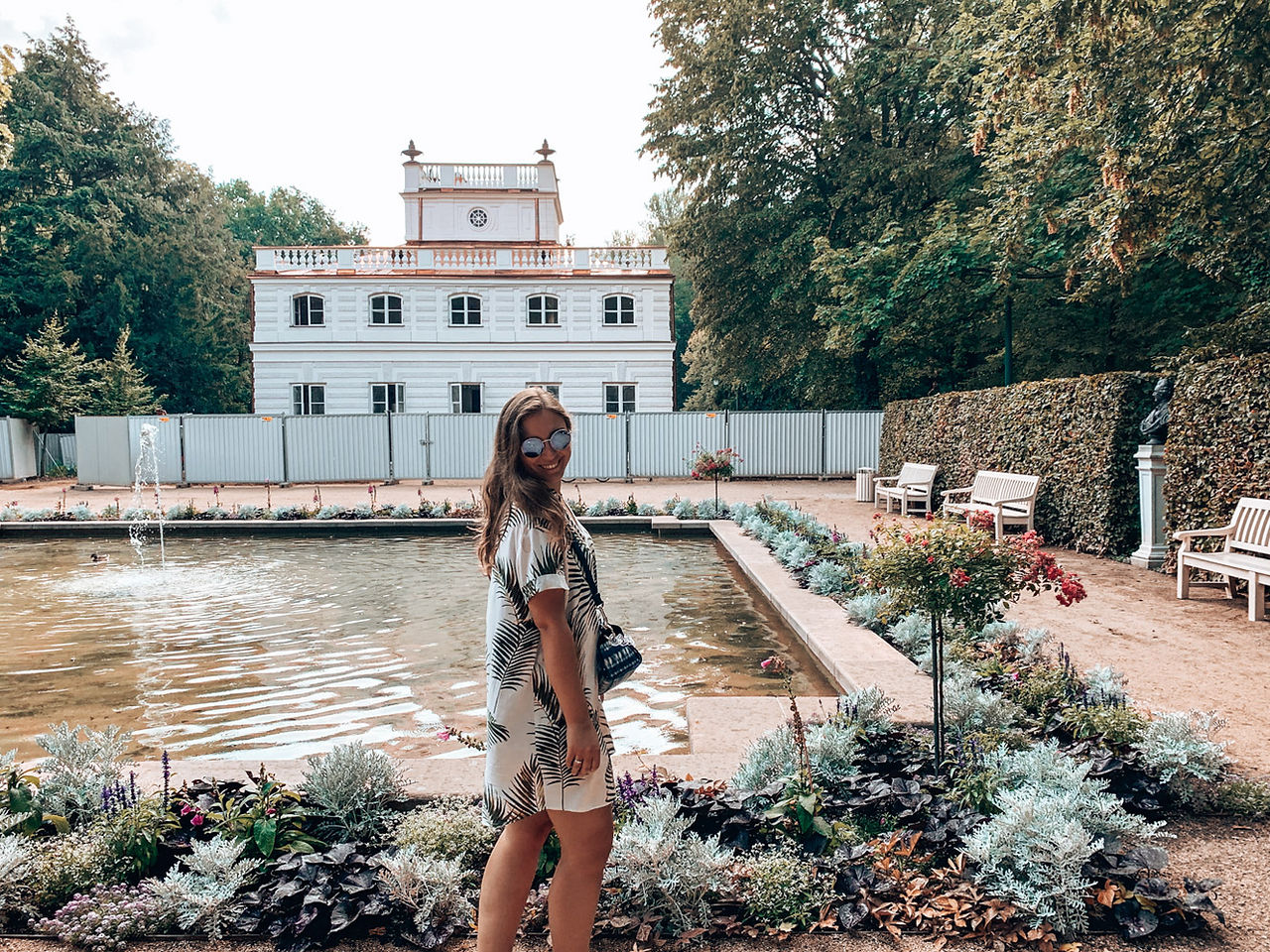 girl in tropical dress posing in front of lake in lazienki park