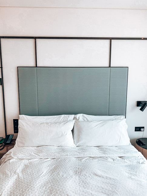 bed with large headboard and white bed sheets