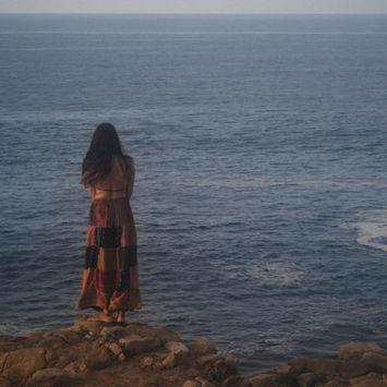 Woman in a patterned skirt looking out at the ocean