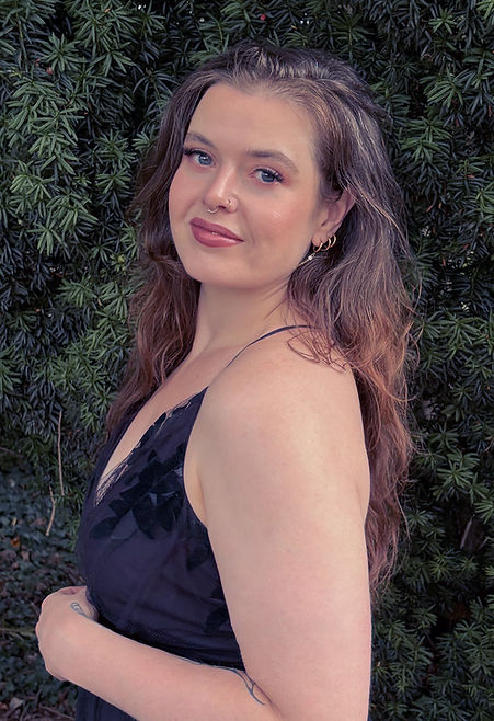 British soprano Rosie Rowell in a black evening gown in a woodland setting