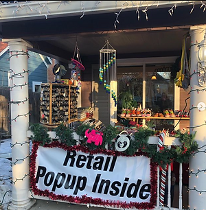 Sign outside of holiday decorated Staufer Realty advertising the holiday pop-up shops inside.