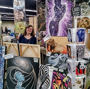 Karen stands inside her booth at the 2018 Spring BMSE, surrounded by her original artwork for sale.
