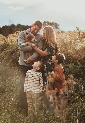 Family taking photos in a field with thier puppy for a fall mini sesson in Baltimore Maryland