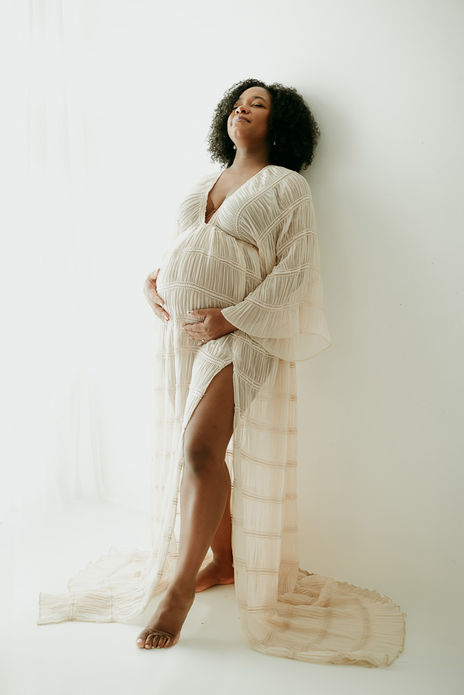 Expecting mom is leaving against a wall thinking about the birth of her baby and taking photos at Tasha Sojka Photography photo studio
