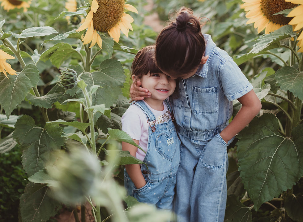 Siblings holding hands surrounded by tall sunflowers in Maryland