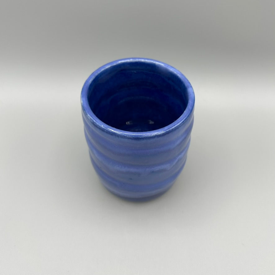 Handcrafted ceramic tumbler with a deep blue glaze and subtle ripple texture, perfect for drinks or as a decorative accent.