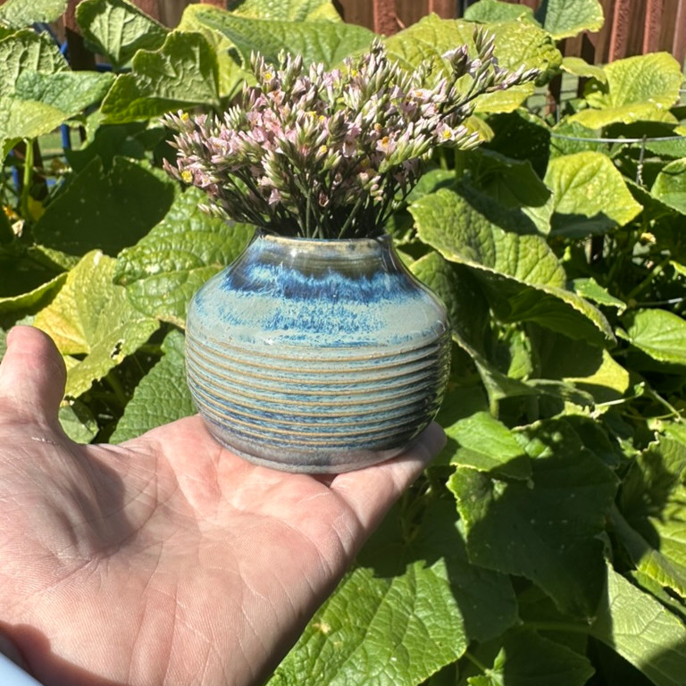 Small ceramic vase with horizontal grooves and a blue-gray glaze with a leafy background.