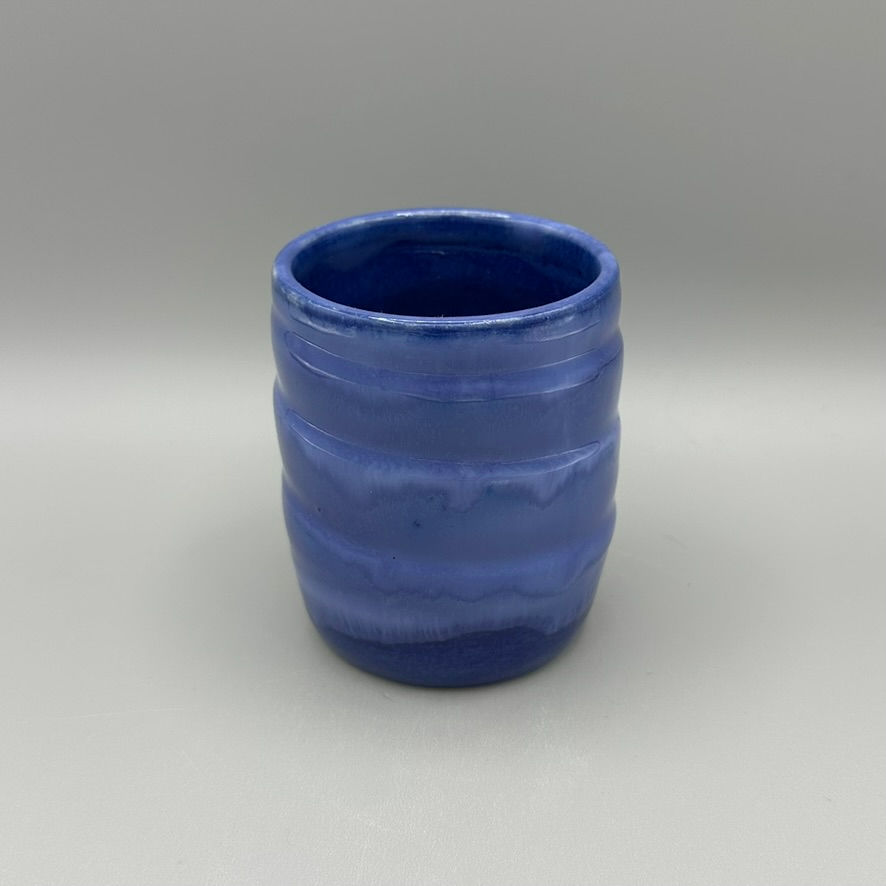 Handcrafted ceramic tumbler with a deep blue glaze and subtle ripple texture, perfect for drinks or as a decorative accent.