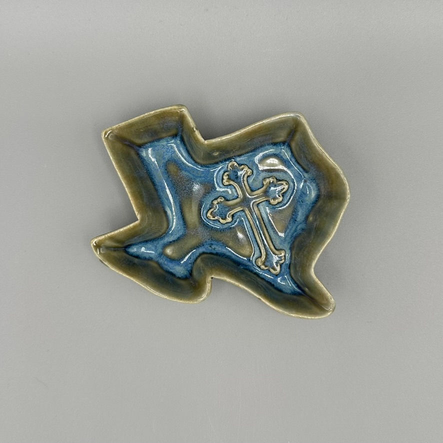 Handcrafted ceramic dish in the shape of Texas with a cross design in the center and a blue and earthy glaze.