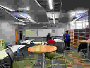 4 people speaking with each other at the front of a classroom