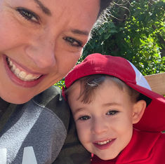 Mom sits with toddler wearing a red and white baseball hat