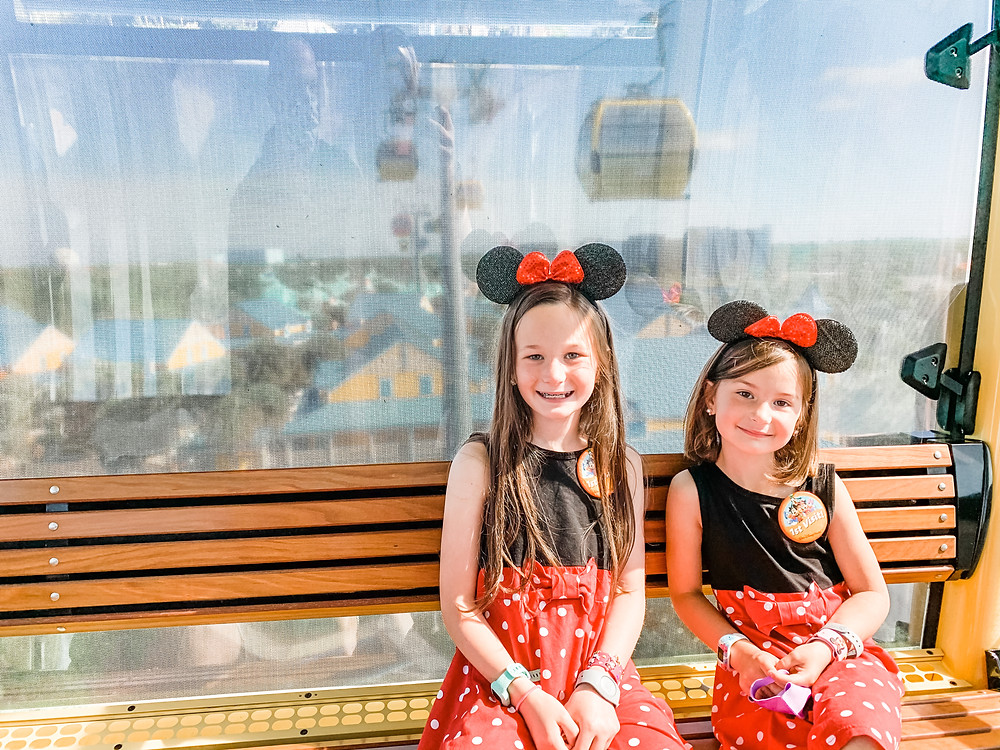 two-girls-sit-on-bench-at-Disney-World-with-Mickey-Mouse-hats