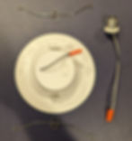 The image displays a new LED retrofit downlight with a white baffle trim. It's designed to be installed into existing recessed lighting fixtures. The unit consists of a round LED panel, integrated with a white baffle trim to reduce glare, and two spring-loaded clips on either side to secure the downlight to the ceiling. There's also an E26 screw base adapter with a two-wire connector, indicating that the downlight can be easily connected to the existing light socket. This type of lighting is energy-efficient and often used to replace traditional incandescent bulbs for a more modern and efficient lighting solution.