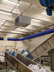 Industriële luchtreiniger met kleding en transportbanden in een grote hal CleanAirNederland
