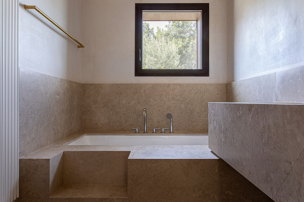 bagno con vasca divestita in pietra e finestra su vegetazione