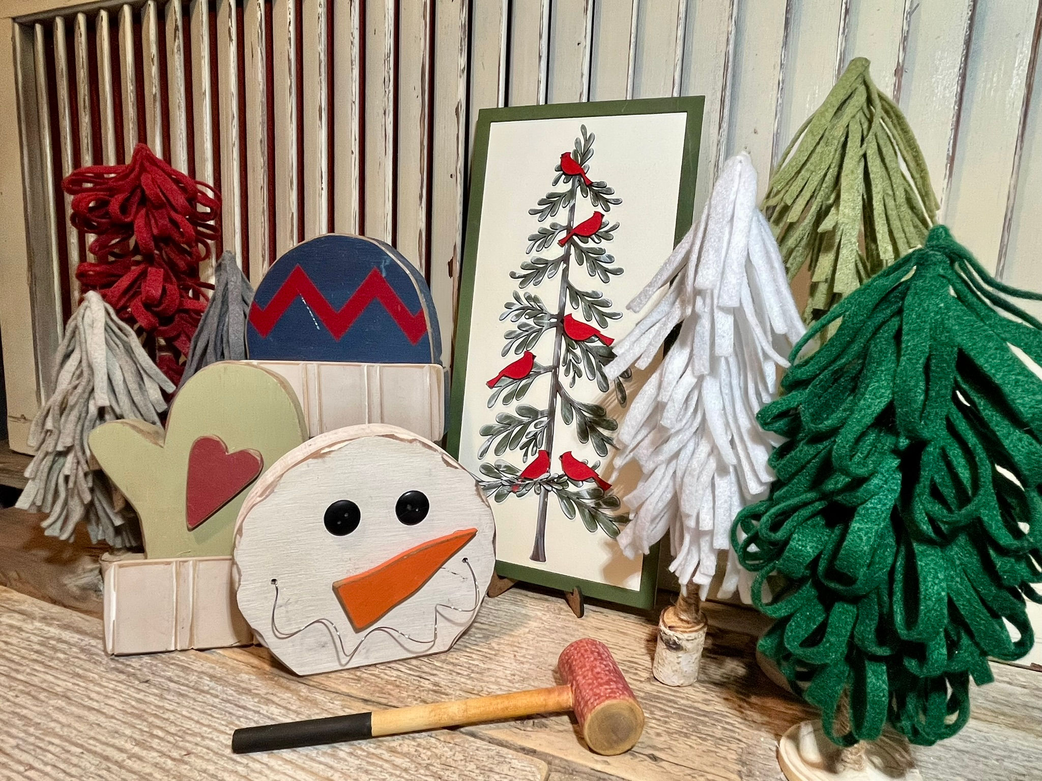 Painted winter craft kit sign featuring a pine tree with red birds, framed and displayed with layered felt trees, snowman cut
