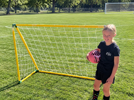 Circo PVC Soccer Goal with Yellow pipe with smiling girl and pink soccer ball on a grass field