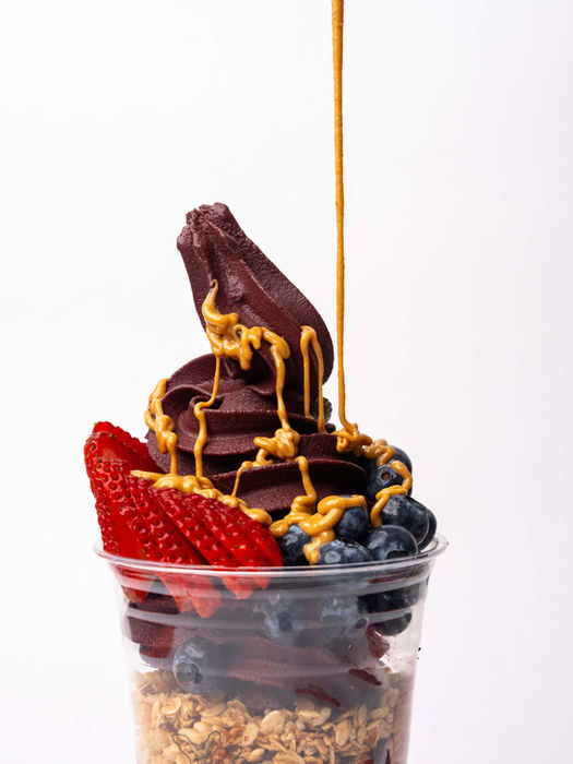 frozen yougurt with fresh fruit and a carmel drizzle coming down