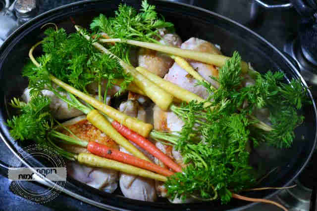 מחזירים לסיר את העוף ומניחים מעליו את הגזרים הגמדיים