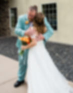 Father of the bride and bride hugging in front of the church