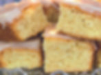 Close-up of stacked lemon drizzle cake squares on a glass plate, showcasing moist texture and glossy icing in a cozy setting.