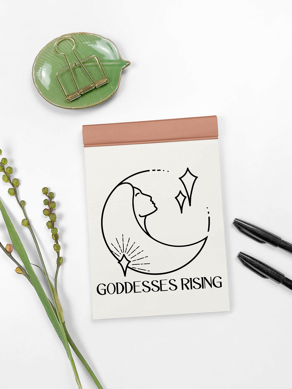 Black circular logo with crescent moon forming a woman's face, with star details and text "Goddesses Rising" beneath.