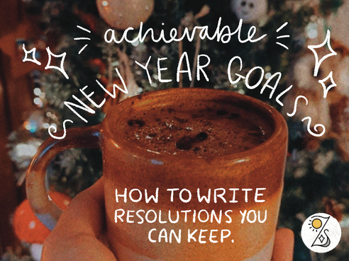 Hand holding a brown mug with hot chocolate in front of a Christmas tree. Text overlays: "Achievable New Year Goals" and "How to write resolutions you can keep." The Loz Sandom Studios logo is in the bottom right-hand corner.