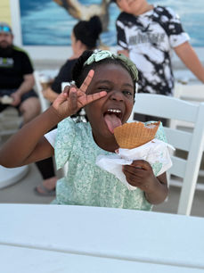 student eating an ice cream cone and holding up two fingers