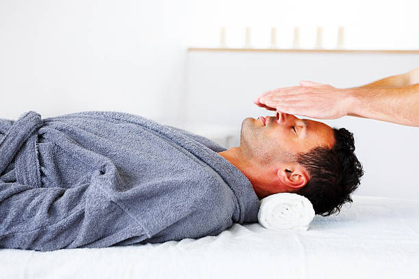 man laying on back receiving reiki from above