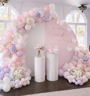 Pastel balloon arch, pedestals, flowers, and pink butterfly backdrop