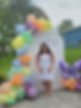 Owner at Happy Mother's Day celebration with pastel balloons and white backdrop with florals throughout and a large butterfly balloon