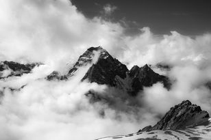 Dramatische Schwarzweißaufnahme eines Gipfels in Wolken und aufsteigendem Nebel, kontrastreich fotografiert von himmelegg.