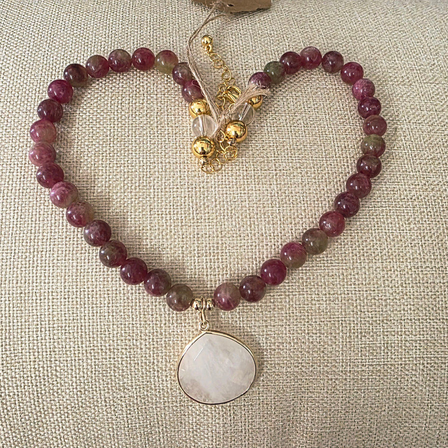 Pink tourmaline, 14k gold-filled beads and a clear quartz pendant in shaped into heart, laying on linen fabric