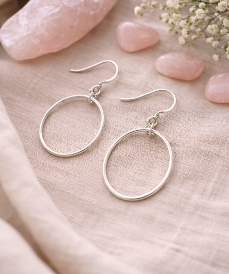 Pair of round sterling silver hoop earrings on linen