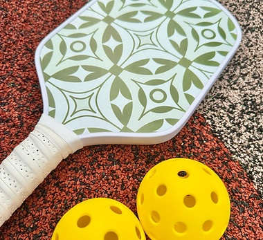 Pickleball paddle and pickleballs on the floor.