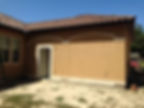 Stucco building exterior with open door and tile roof