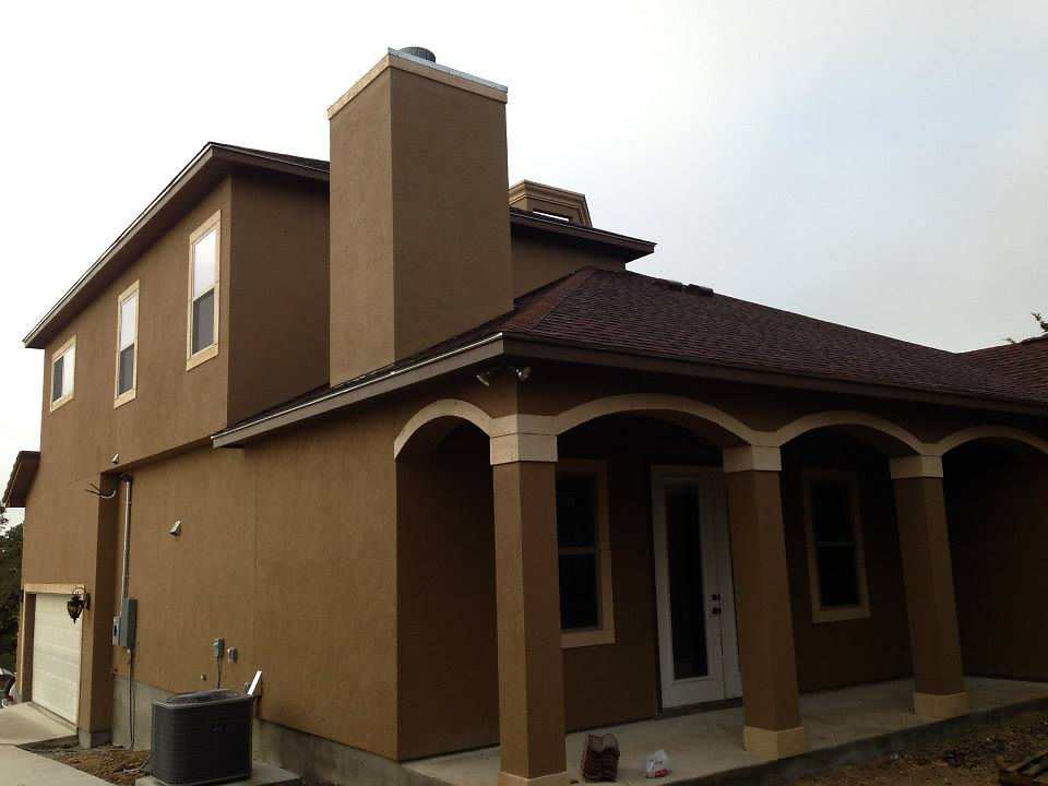 Brown stucco home with covered porch and chimney