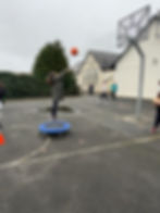 Girl jumps, shooting basketball; school playground