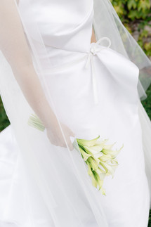 Bride in white dress holding a bouquet of calla lilies
