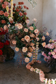  a large, sculptural arrangement of white, pink, and red flowers stands on a clear base