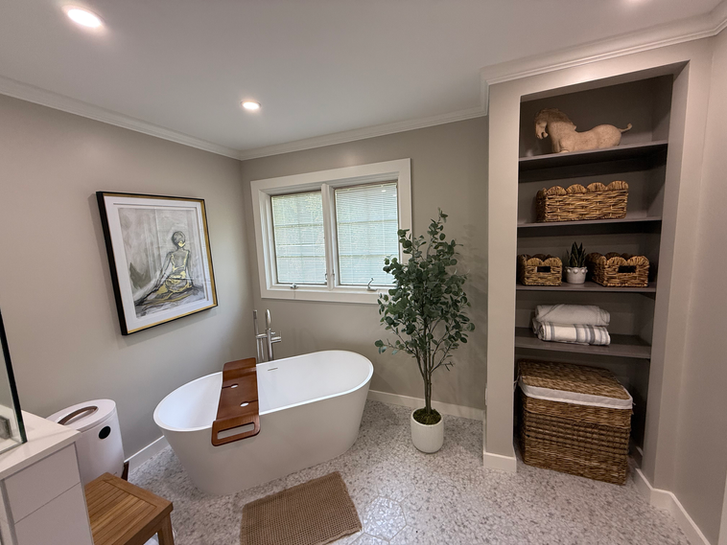 Bathroom remodel in Wyckoff, NJ with freestanding bathtub, shelving, and soft beige tile.