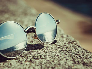 Sunglasses resting on a rock with a clear horizon reflected in the lenses, symbolizing clarity and the Voice of the Customer guiding CX strategy