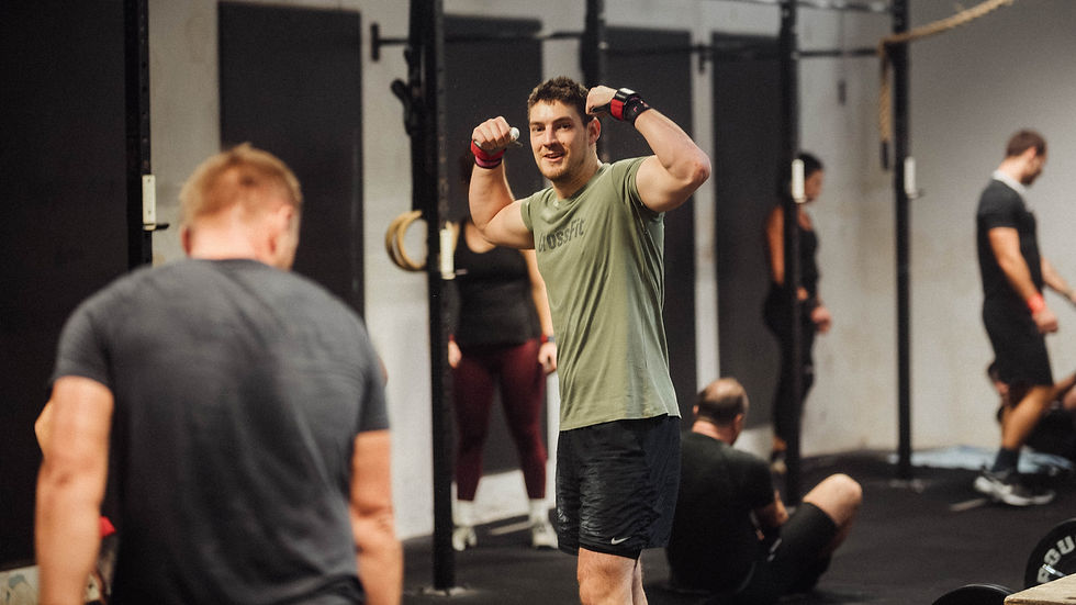 Muškarac pokazuje bicepse usred grupnog funkcionalnog treninga.